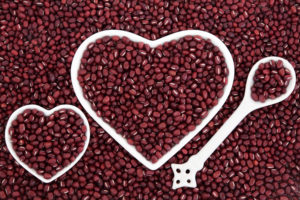 Adzuki bean health food in heart shaped porcelain dishes and spoon forming an abstract background.